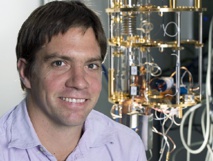 Kater Murch, junto al congelador de diluciones que ha utilizado para enfrir su qubit superconductor. Imagen: Joe Angeles. Fuente: WUSTL.
