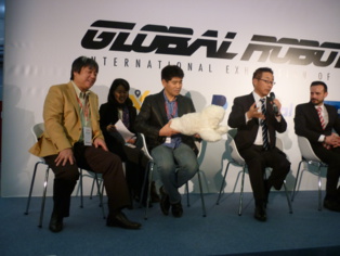 De izquierda a derecha, Hiroshi Kobayashi, la traductora, Takanori Shibata (con la invención de Kobayashi, Paro/Nuka), y el embajador de Japón en España, Kazukiho Koshikawa. Imagen: C. G. A.