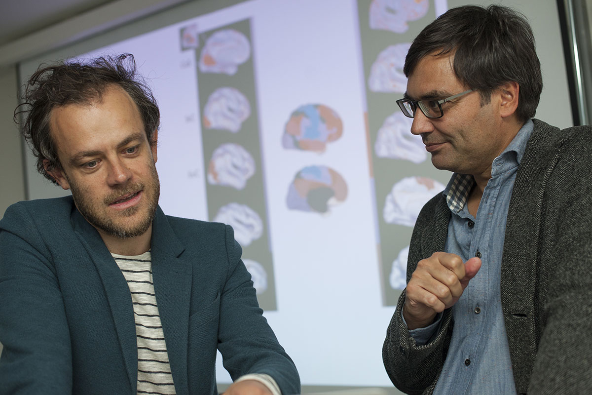 Valentin Riedl (izquierda), líder del grupo de investigación, con su colega, Christian Sorg. Al fondo, imágenes del cerebro en sus diferentes fases del proceso de la visión. (Foto: K. Bauer / TUM)