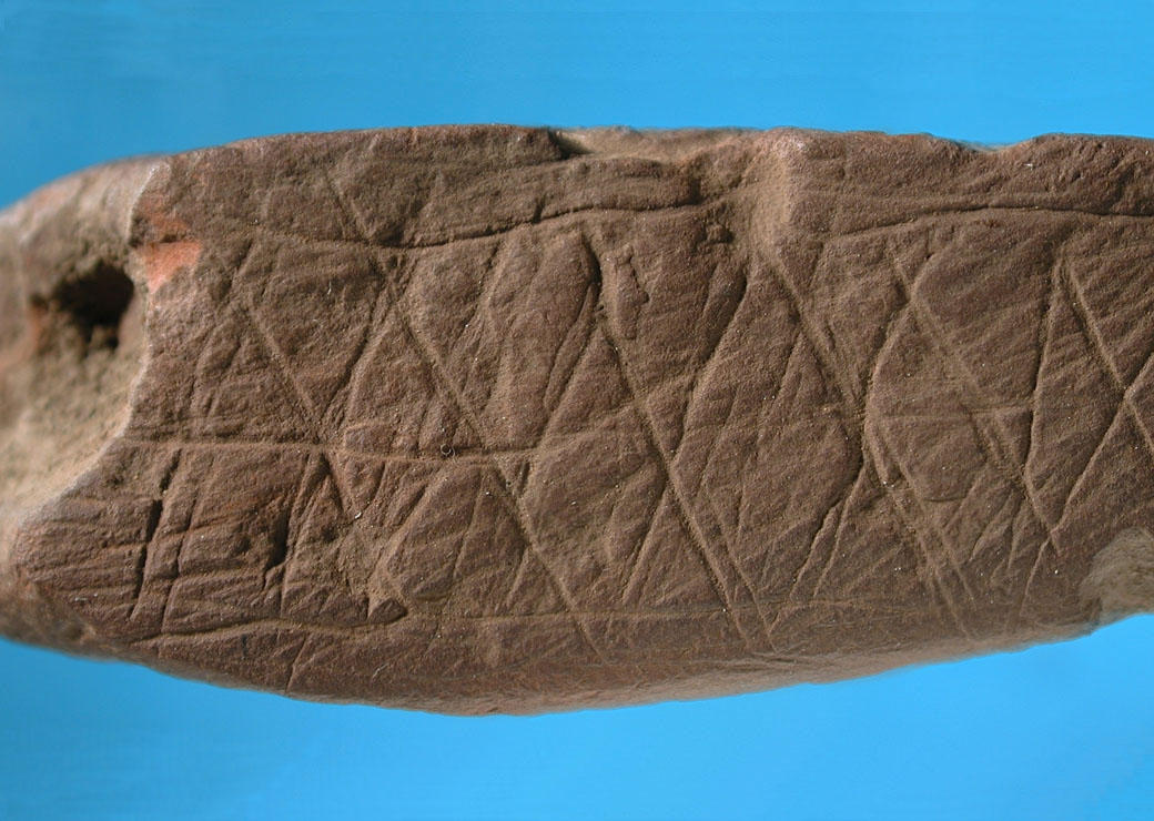 Trozo de ocre grabado con un patrón abstracto en el sitio de Blombos (Sudáfrica) con una antigüedad de 75,000 años. © D'Errico / Henshilwood / Nature. Universidad de Burdeos.