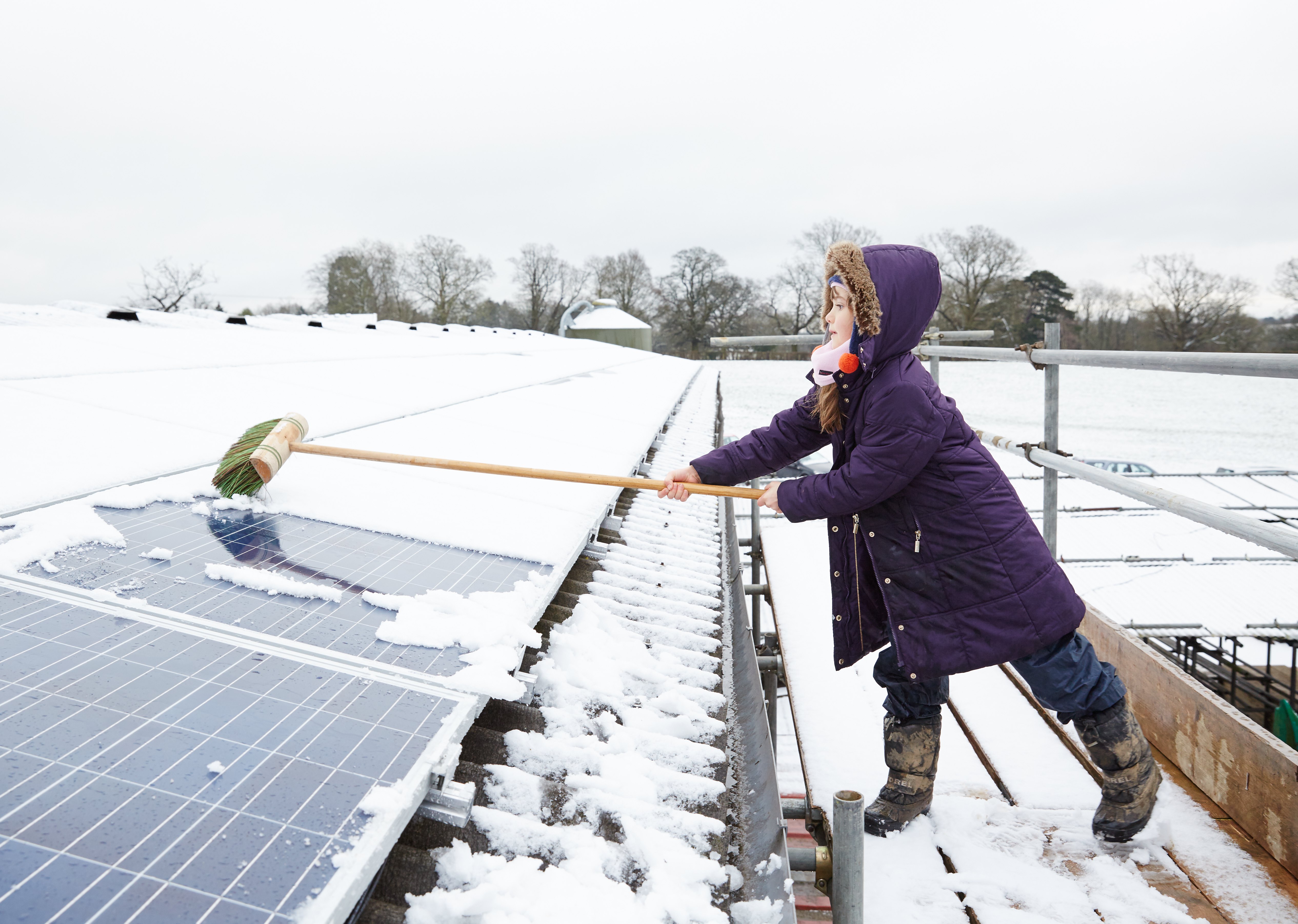 Niña limpiando paneles solares fotovoltaicos de la nieve en Grange Farm, Balcombe, Reino Unido. Foto: Balcombe.