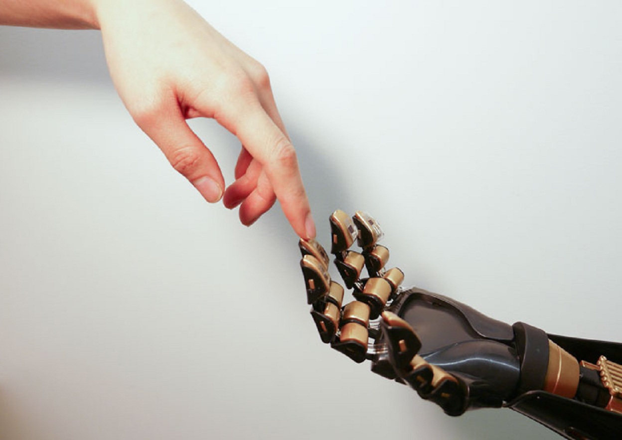 Un dedo humano toca un dedo robótico, revestido con piel artificial. Imagen: Bao Lab. Fuente: Universidad Stanford.