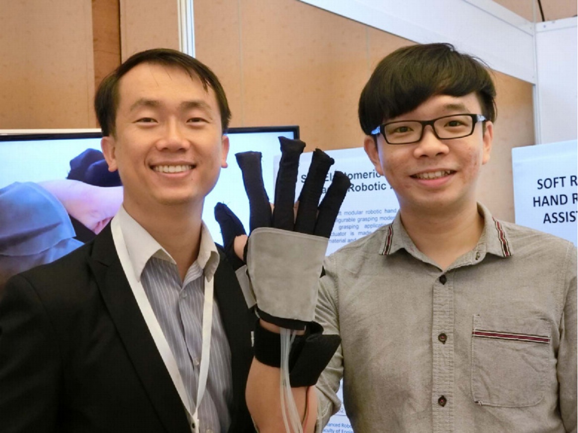 El doctor Raye Yeow (izq) con el profesor Yap Hong Kai mostrando su guante robótico. Fuente: NUS