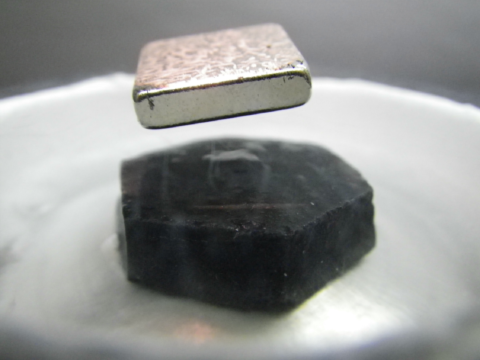 Un imán, levitando sobre un cuprato superconductor. Imagen: Robert Hill. Fuente: Universidad de Waterloo.